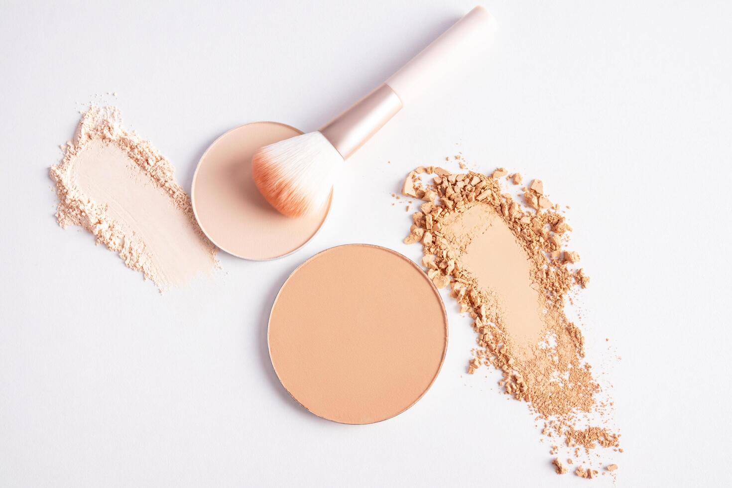 cosmetic background with texture samples of compact and loose powder in different tones. A chic makeup brush. top view. white background photo