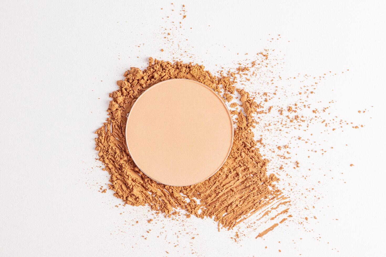 A round block of compact powder in a natural tone stands on a sample of loose powder in a dark tone. top view.textures of powders. layout. photo