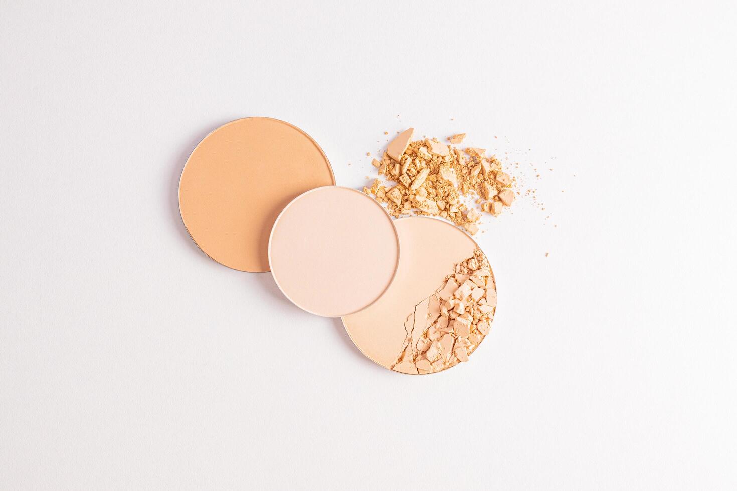 Three chic round blocks of compact powder closeup on a loose powder sample. top view. White background. The texture of the powder product photo