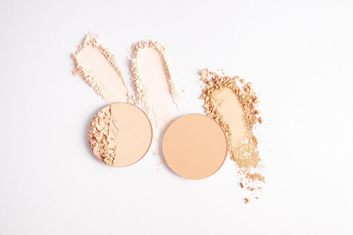 Samples of compact powder and loose powder of different tones, strokes, blocks on a white background. top view. texture of various powders. layout. photo
