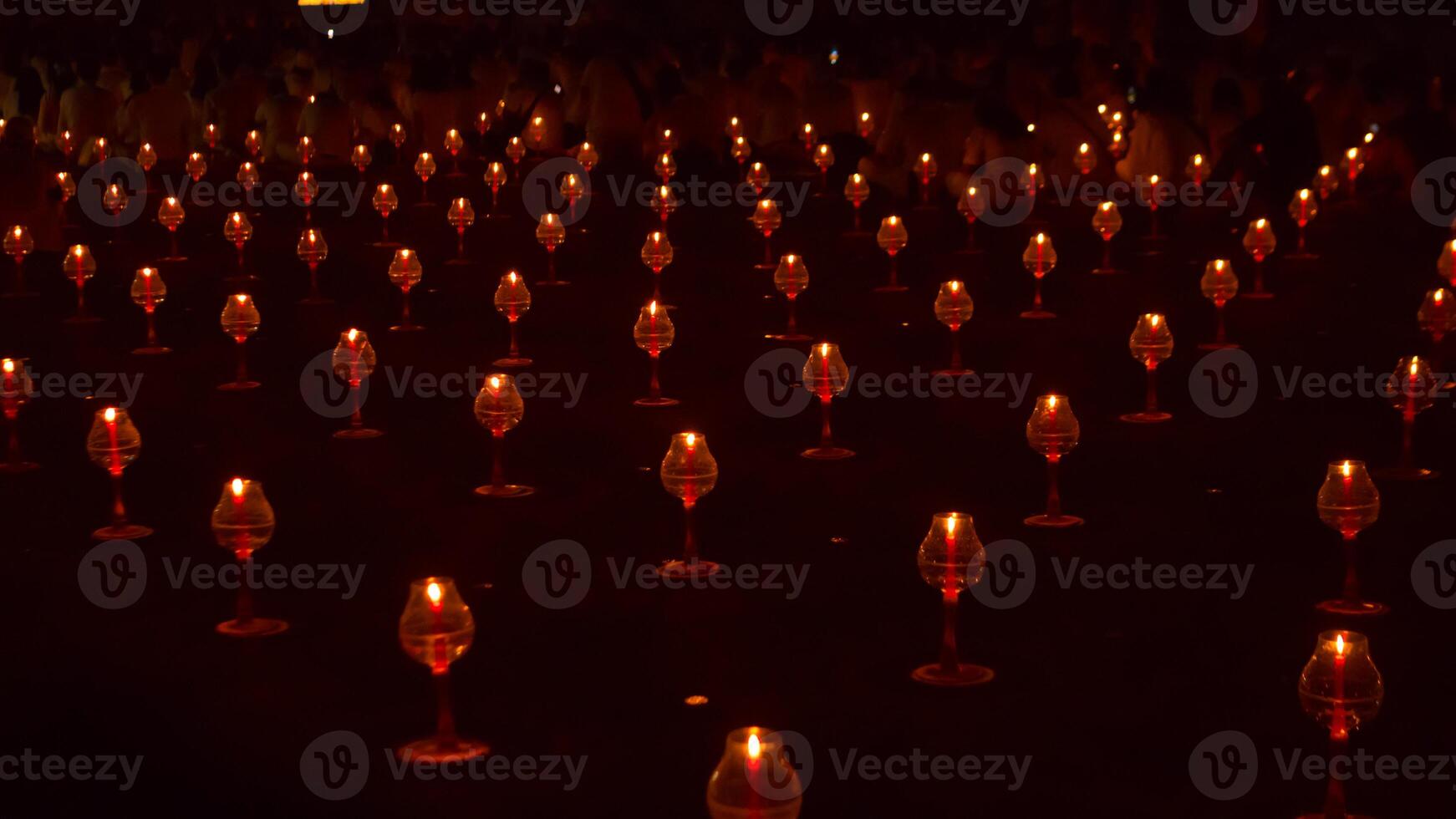 A large number of candles are lit at borobudur temple. The candles are arranged in a pattern, with some candles grouped together and others spaced apart. Scene is one of warmth and coziness photo