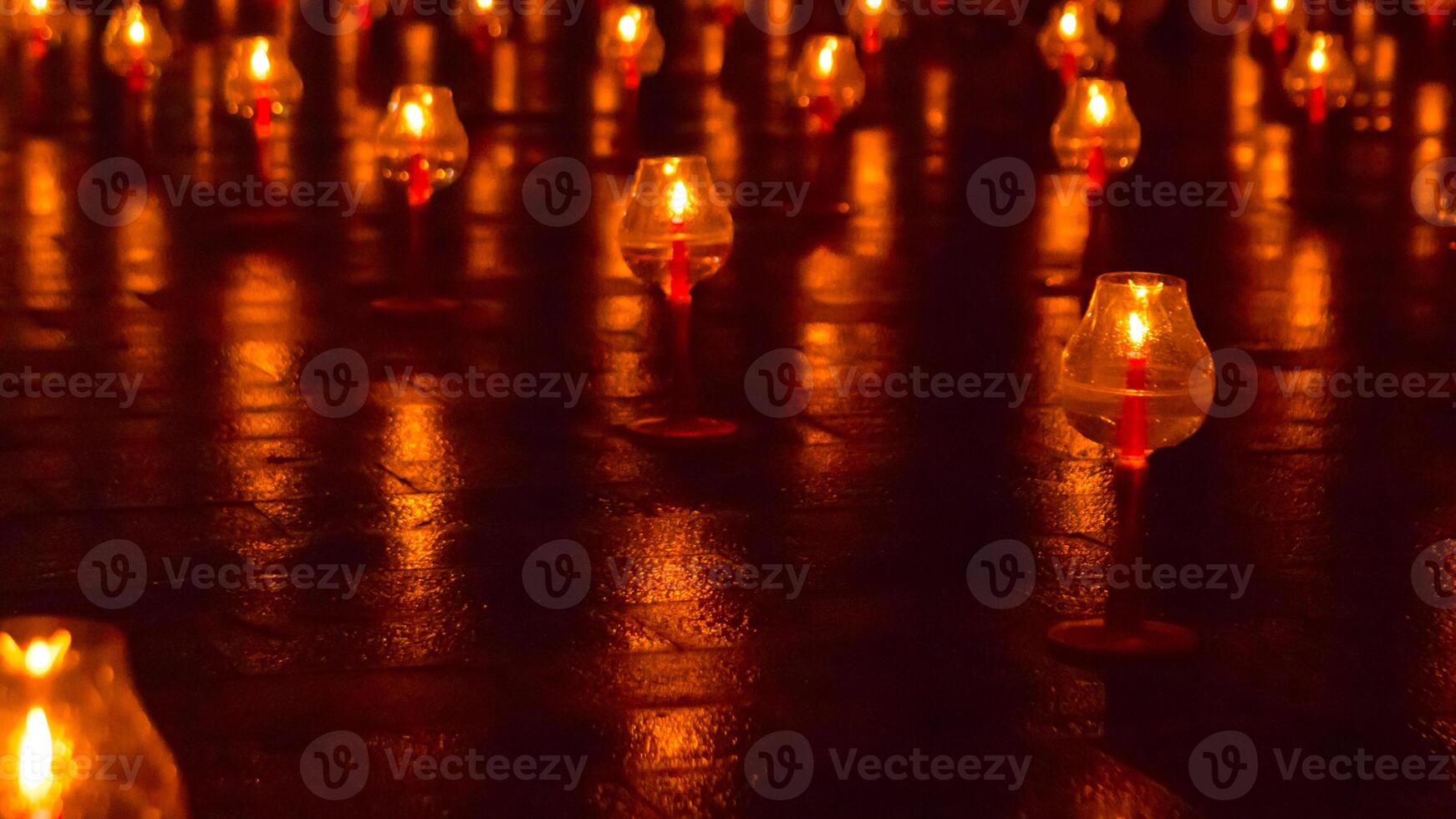 A large number of candles are lit at borobudur temple. The candles are arranged in a pattern, with some candles grouped together and others spaced apart. Scene is one of warmth and coziness photo