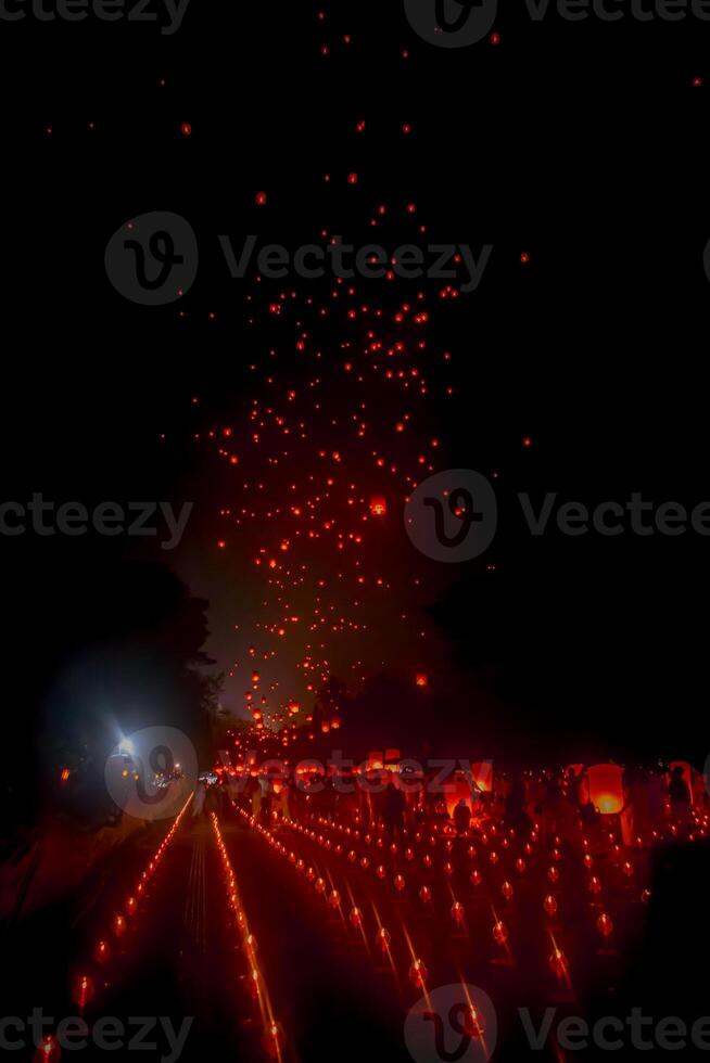 A large group of Buddhist people at Borobudur temple holding burning candles and lanterns. The scene is illuminated with warm, inviting light, creating a festive atmosphere photo