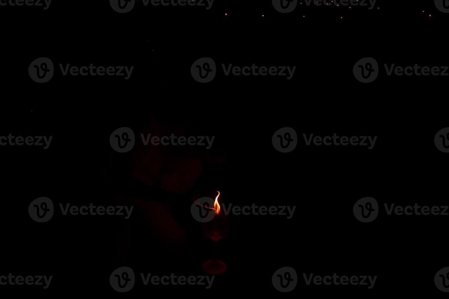 A person is holding a candle in a dark room. The candle is lit and the room is dimly lit photo