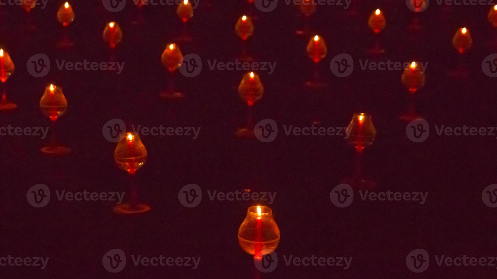 A large number of candles are lit at borobudur temple. The candles are arranged in a pattern, with some candles grouped together and others spaced apart. Scene is one of warmth and coziness photo
