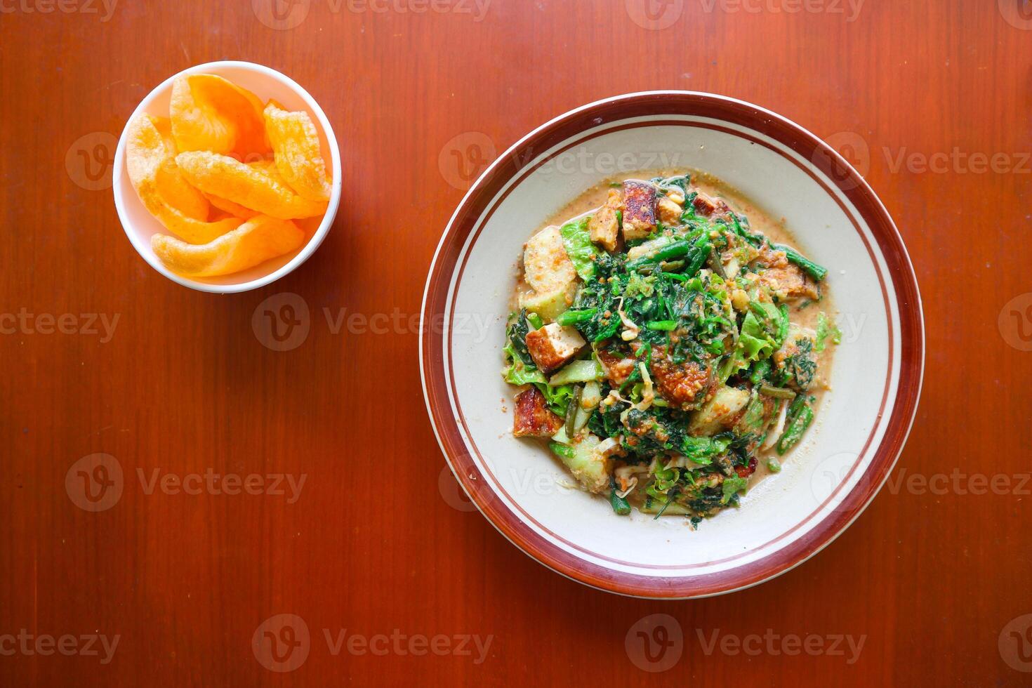 lotek is a traditional salad from Indonesia made from vegetable, chayote, kale, young jackfruit, tempeh, tofu, long beans, and bean sprouts with peanut sauce and cracker photo