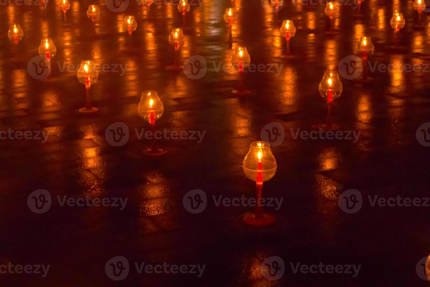 A large number of candles are lit at borobudur temple. The candles are arranged in a pattern, with some candles grouped together and others spaced apart. Scene is one of warmth and coziness photo