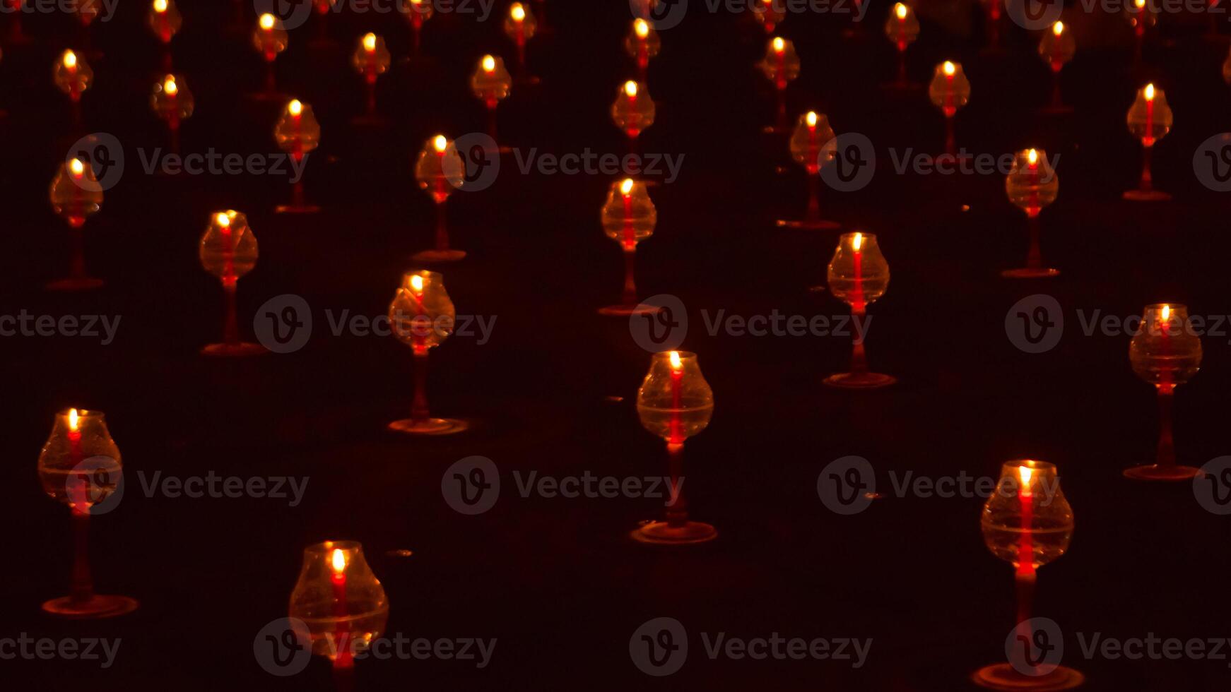A large number of candles are lit at borobudur temple. The candles are arranged in a pattern, with some candles grouped together and others spaced apart. Scene is one of warmth and coziness photo