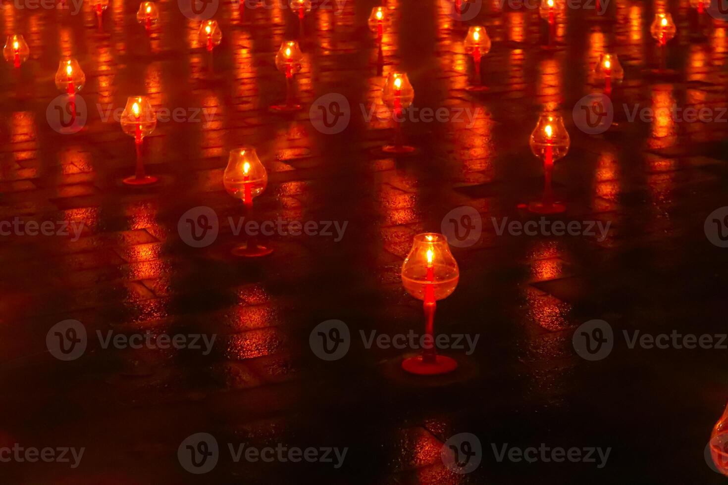 A large number of candles are lit at borobudur temple. The candles are arranged in a pattern, with some candles grouped together and others spaced apart. Scene is one of warmth and coziness photo