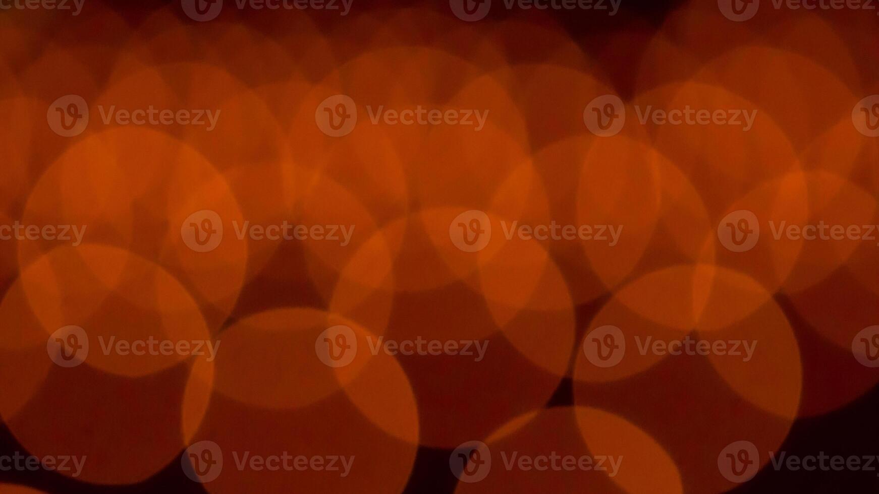 bokeh blurry, orange and black photo of a bunch of small circles. The circles are all different sizes and are scattered throughout the photo. Scene is somewhat chaotic and disorganized