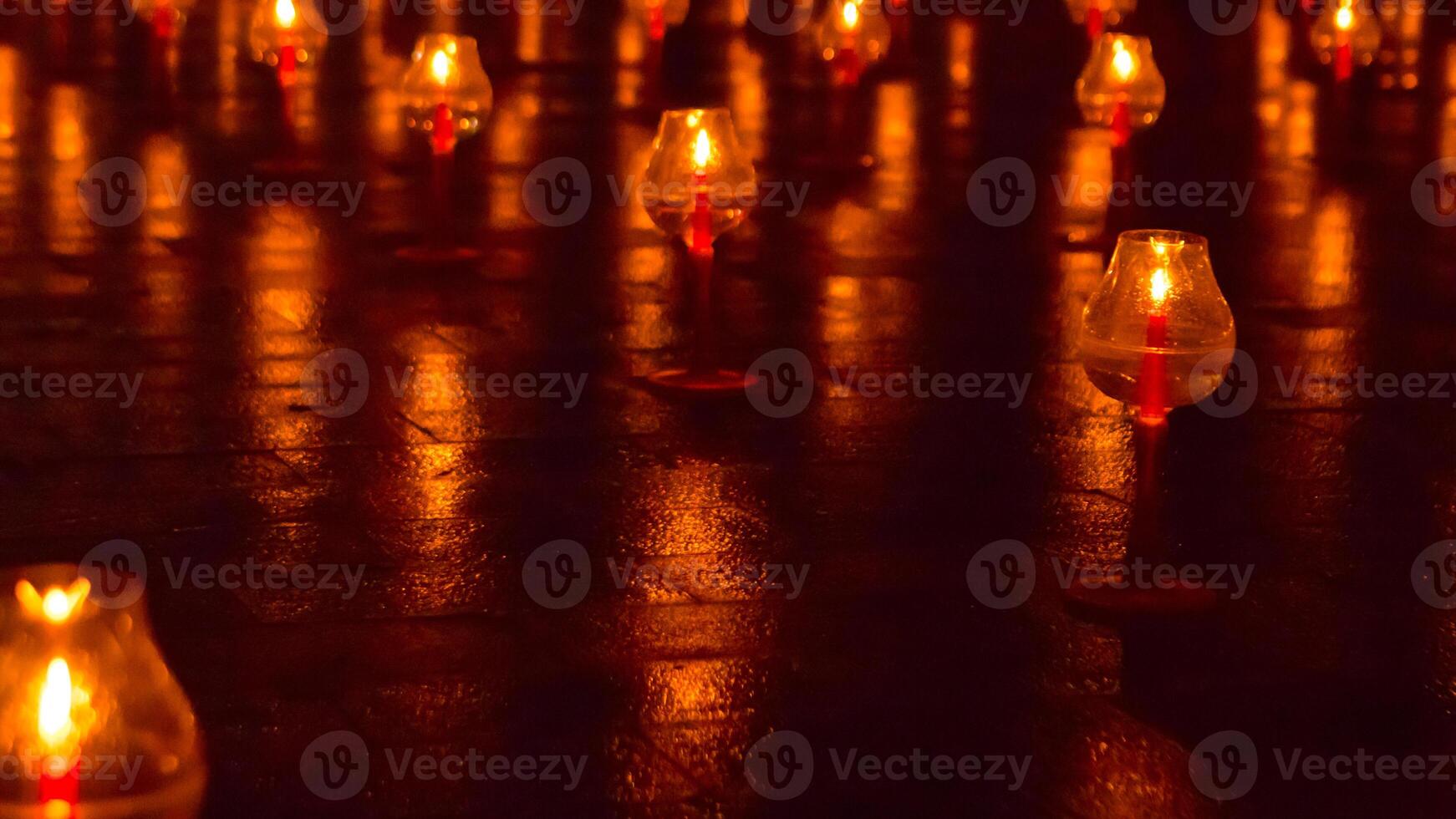 A large number of candles are lit at borobudur temple. The candles are arranged in a pattern, with some candles grouped together and others spaced apart. Scene is one of warmth and coziness photo