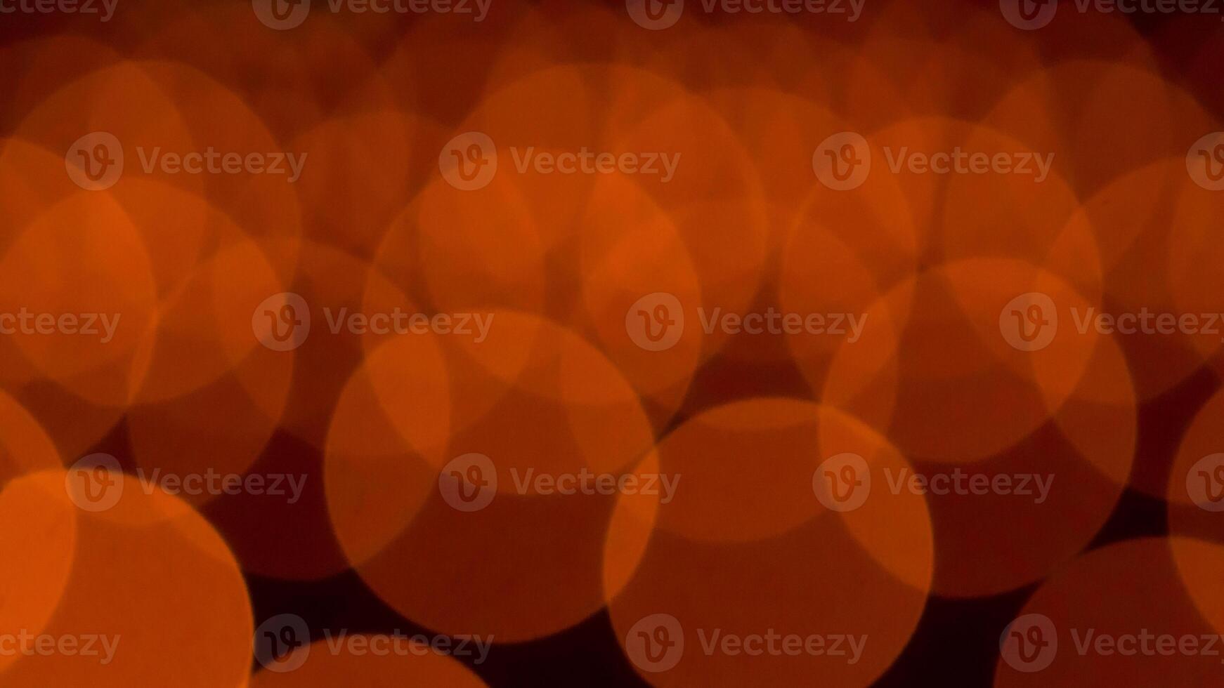 bokeh blurry, orange and black photo of a bunch of small circles. The circles are all different sizes and are scattered throughout the photo. Scene is somewhat chaotic and disorganized