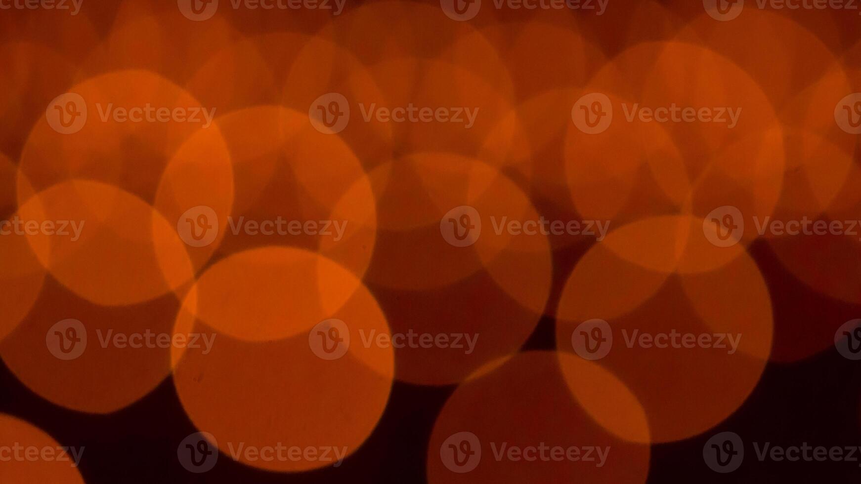 bokeh blurry, orange and black photo of a bunch of small circles. The circles are all different sizes and are scattered throughout the photo. Scene is somewhat chaotic and disorganized