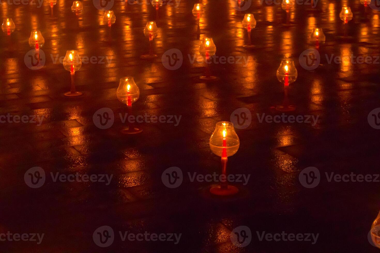 A large number of candles are lit at borobudur temple. The candles are arranged in a pattern, with some candles grouped together and others spaced apart. Scene is one of warmth and coziness photo