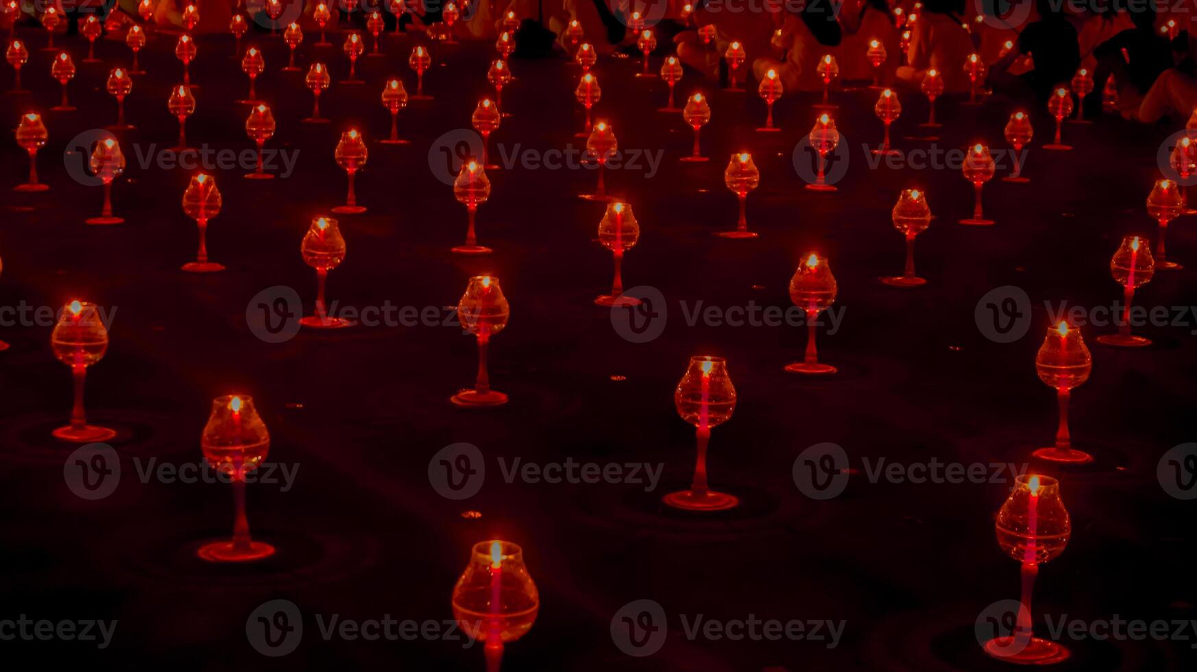 A large number of candles are lit at borobudur temple. The candles are arranged in a pattern, with some candles grouped together and others spaced apart. Scene is one of warmth and coziness photo