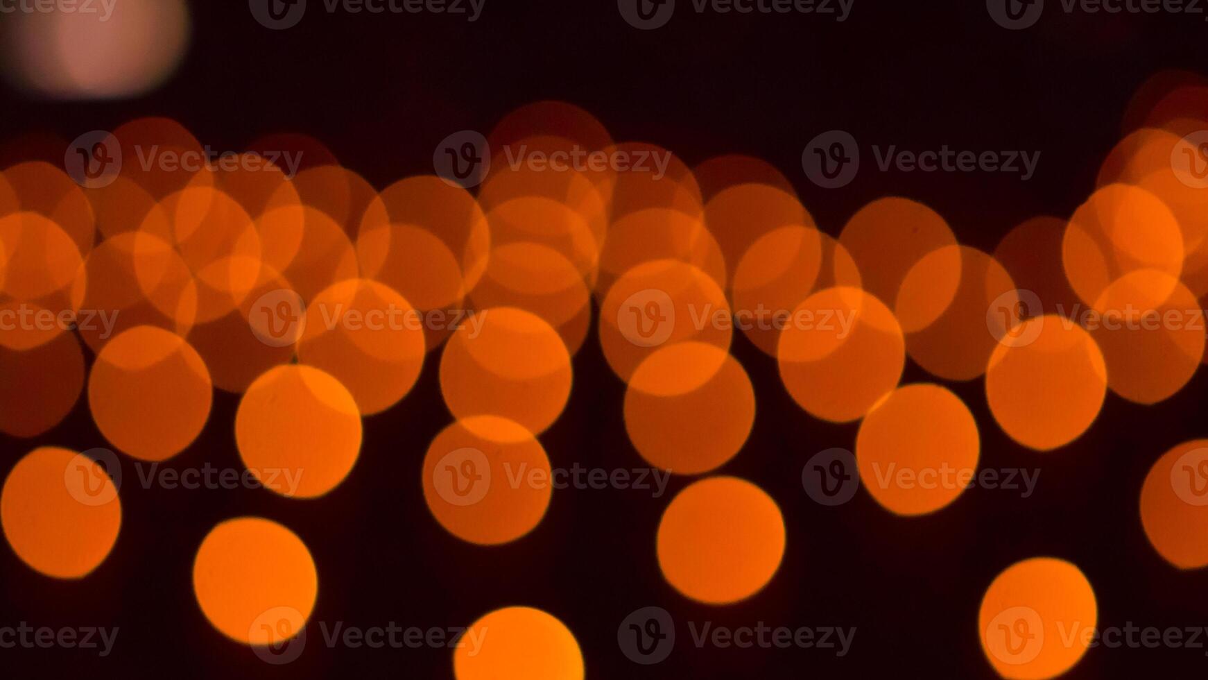 bokeh blurry, orange and black photo of a bunch of small circles. The circles are all different sizes and are scattered throughout the photo. Scene is somewhat chaotic and disorganized