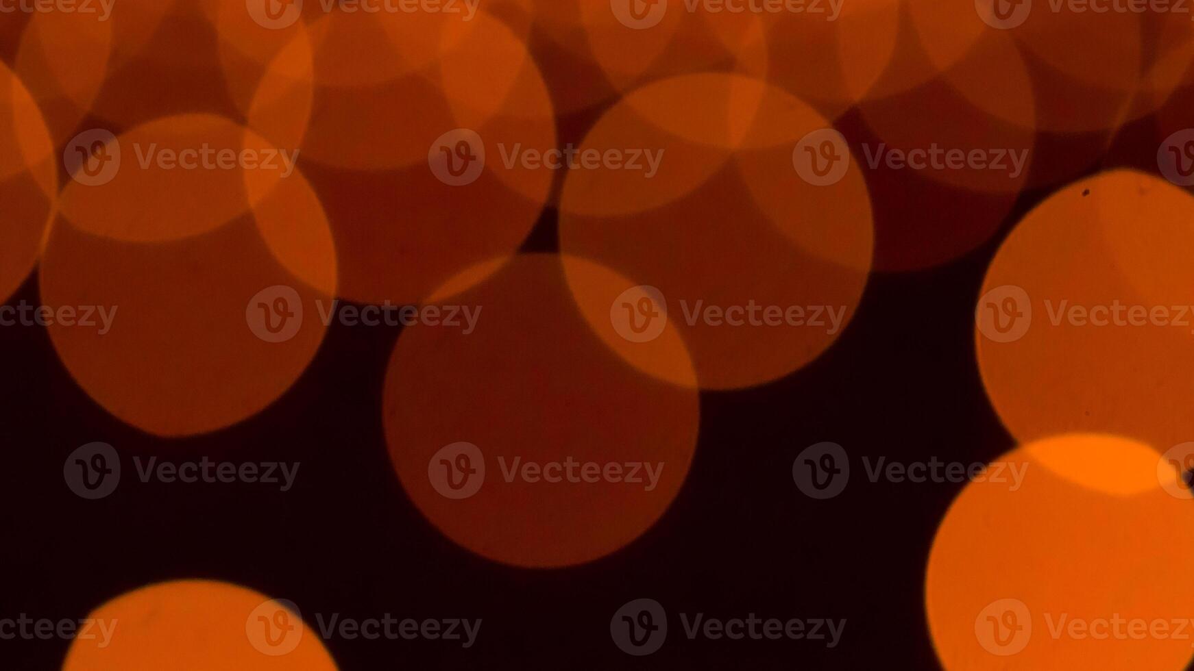 bokeh blurry, orange and black photo of a bunch of small circles. The circles are all different sizes and are scattered throughout the photo. Scene is somewhat chaotic and disorganized