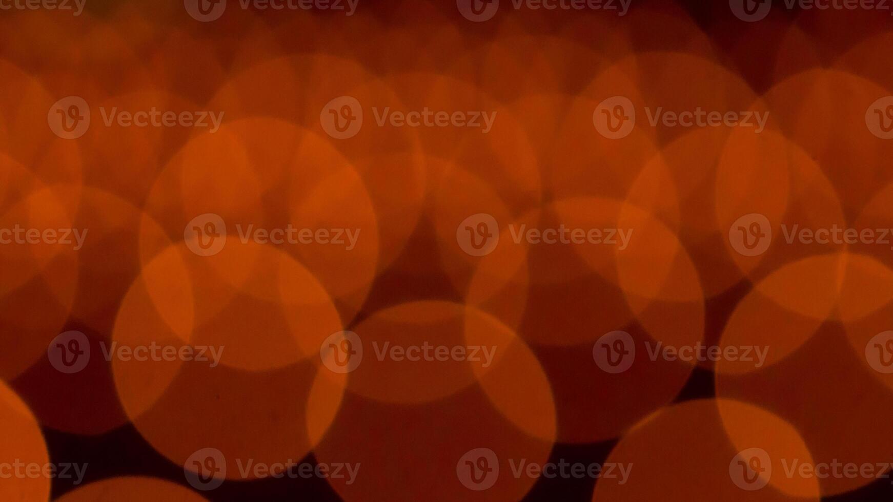 bokeh blurry, orange and black photo of a bunch of small circles. The circles are all different sizes and are scattered throughout the photo. Scene is somewhat chaotic and disorganized
