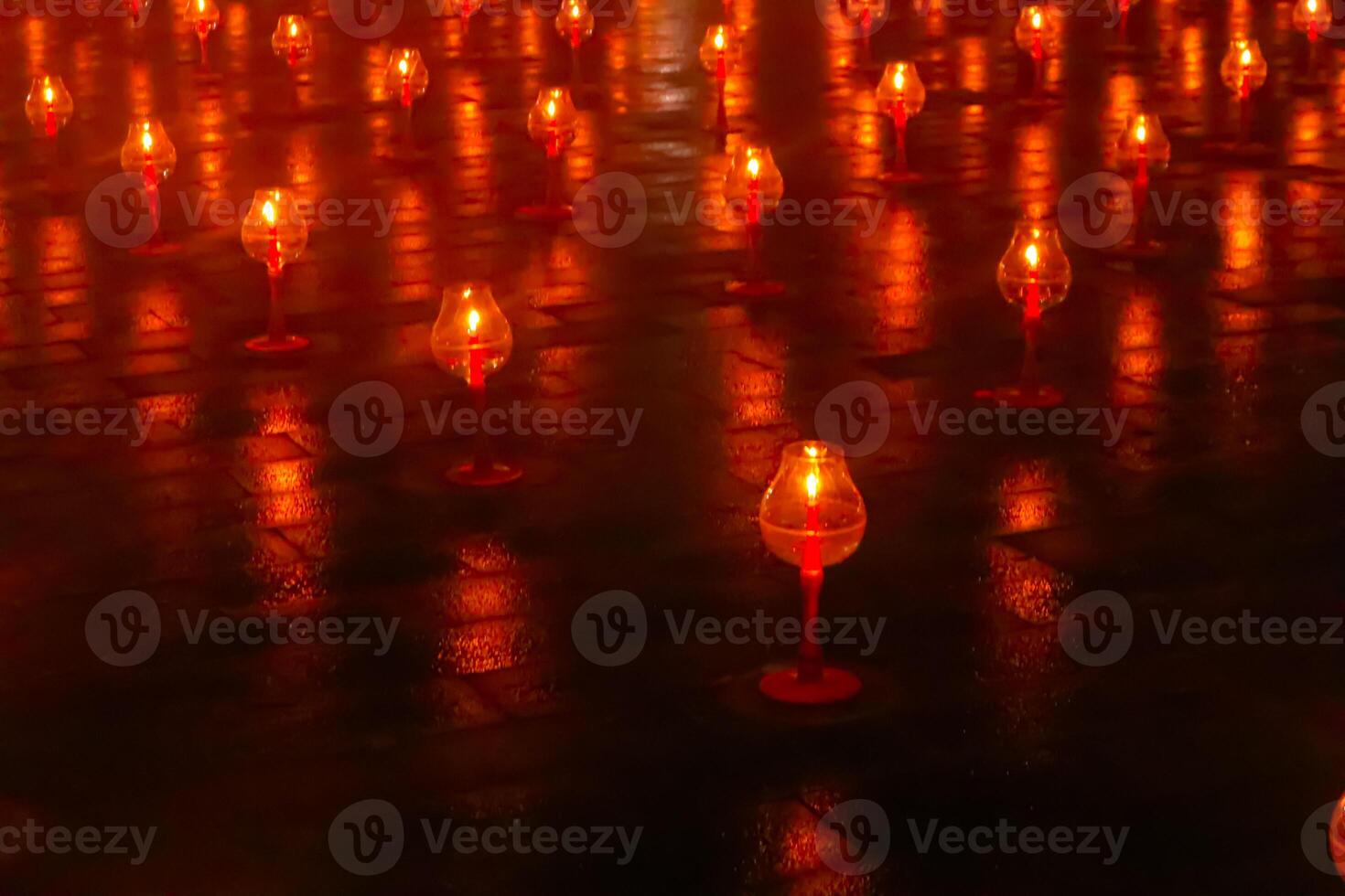 A large number of candles are lit at borobudur temple. The candles are arranged in a pattern, with some candles grouped together and others spaced apart. Scene is one of warmth and coziness photo