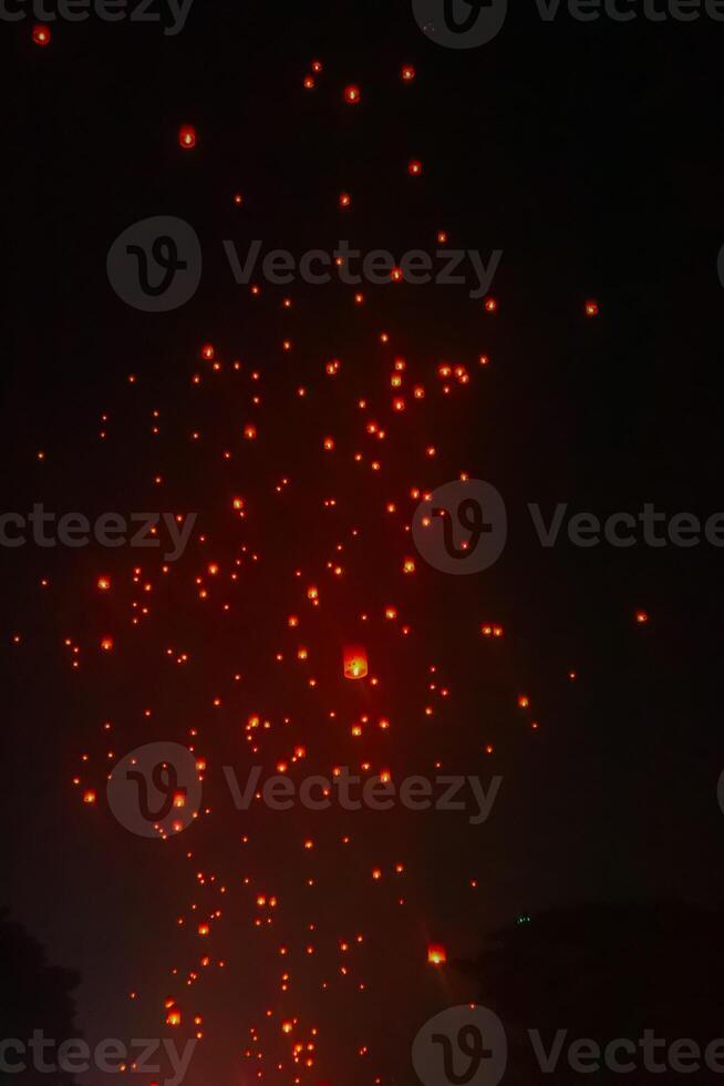 A large group of Buddhist people at Borobudur temple holding burning candles and lanterns. The scene is illuminated with warm, inviting light, creating a festive atmosphere photo