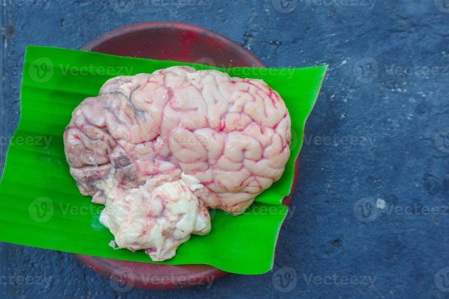 Brain cow is on a green leaf. The Brain cow is cut in half and has a red and white color photo