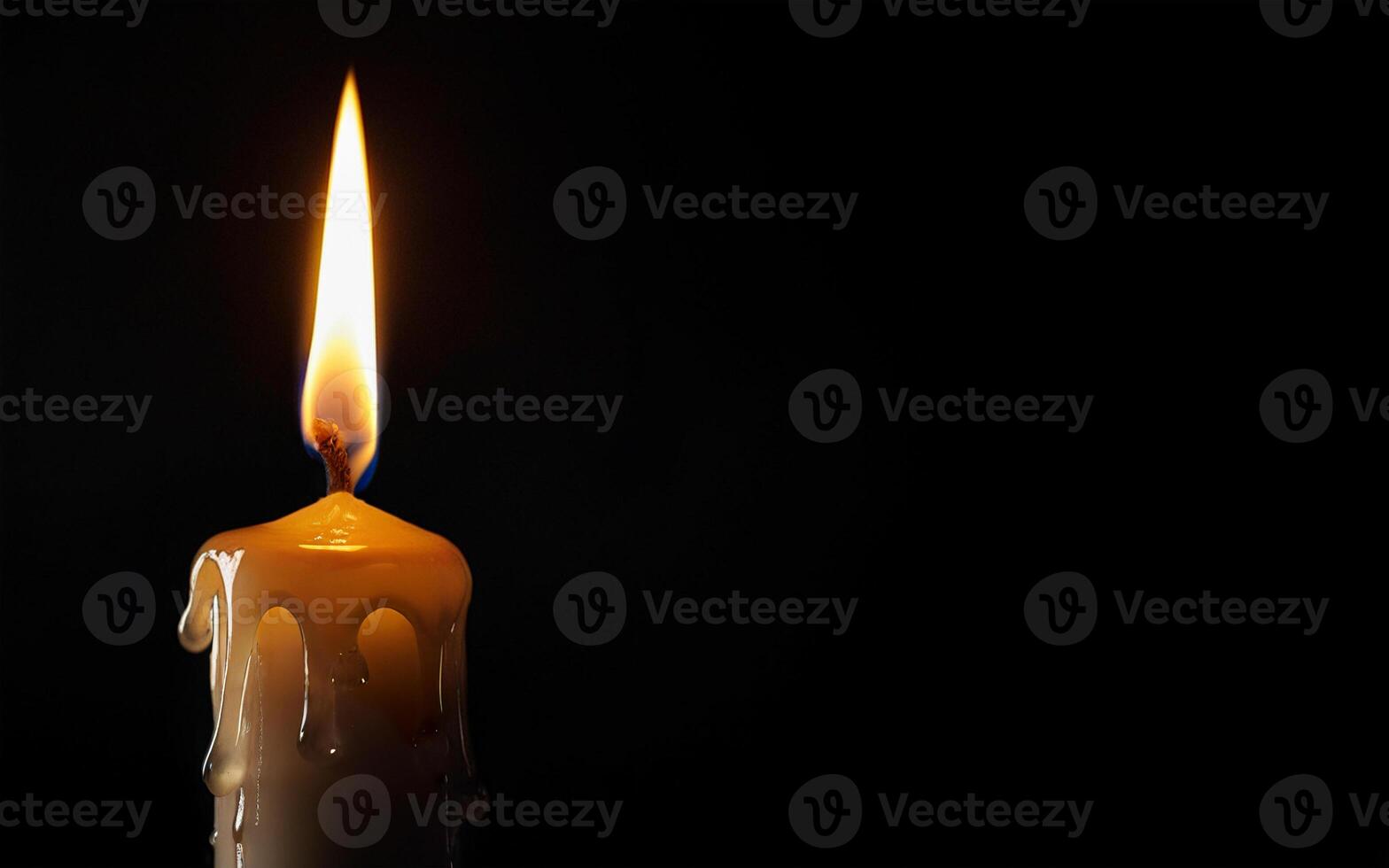 burning yellow candle and dripping wax on a black background with space for text photo
