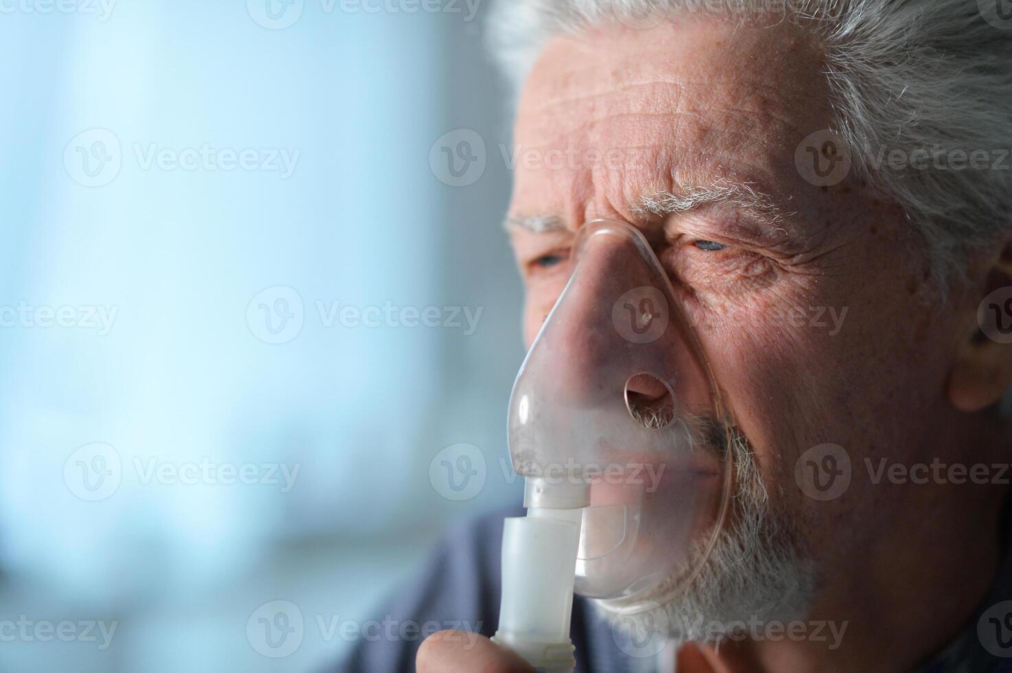 Portrait of sick senior man doing inhalation photo
