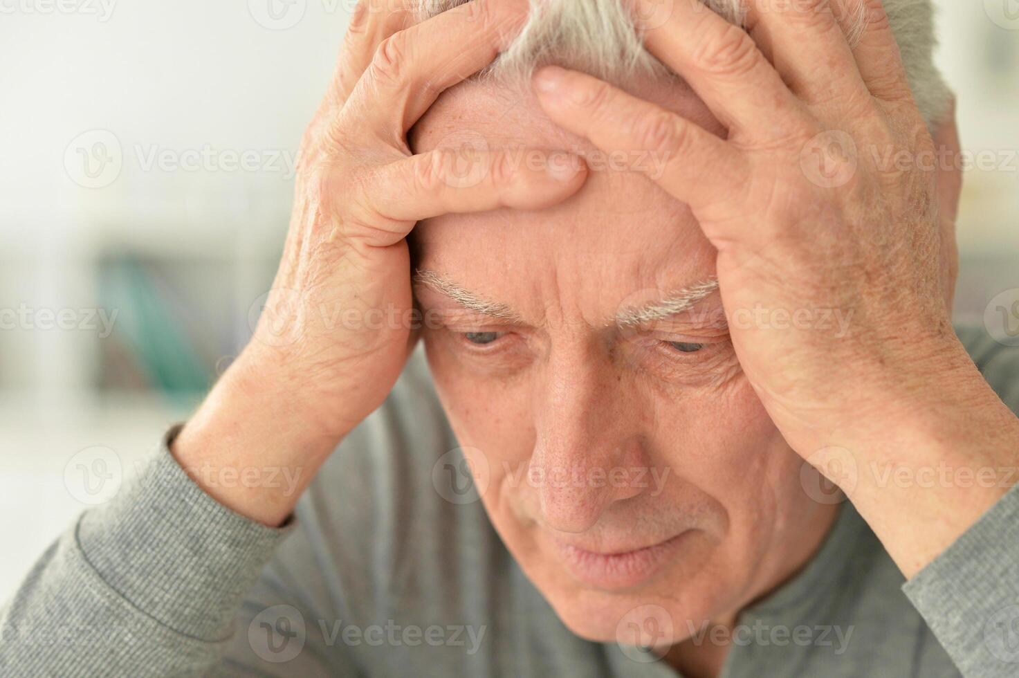 Elderly man suffering from a headache at home photo