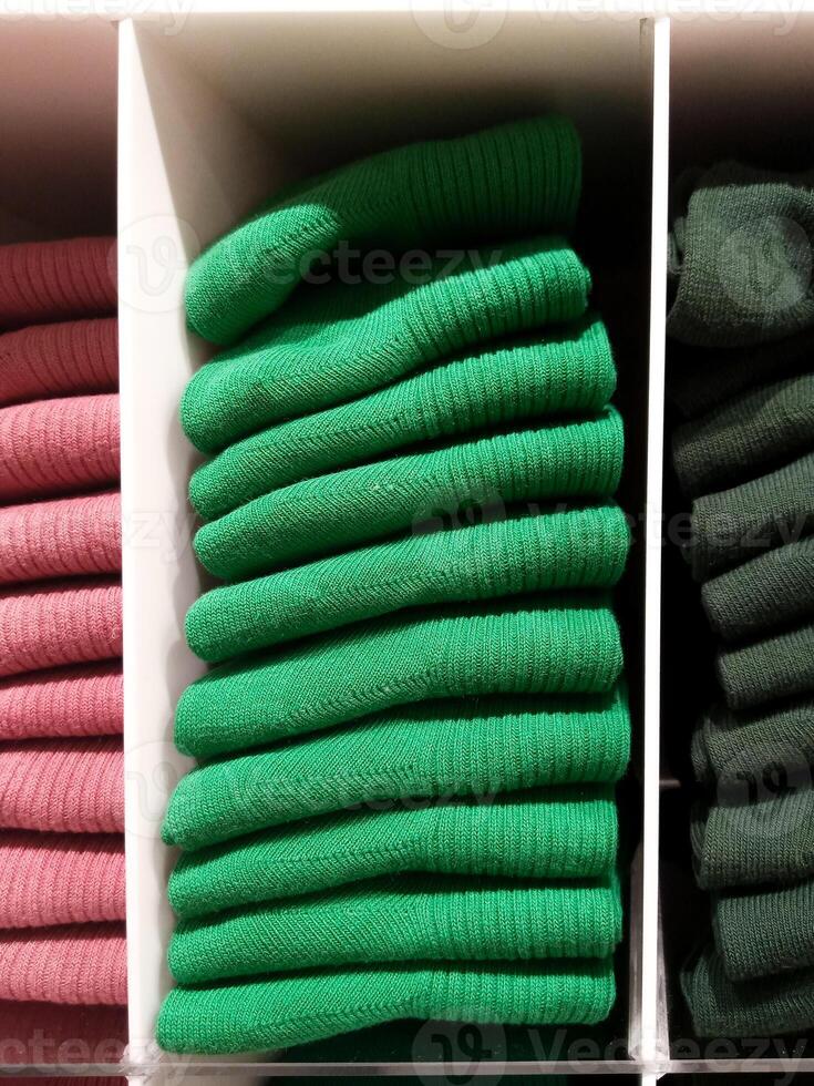 Stacks of colorful clothes on retail store shelves. photo