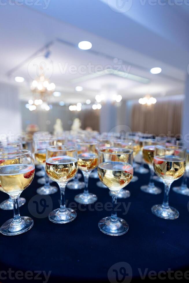 A table full of wine glasses with a blue background. Scene is celebratory and festive photo