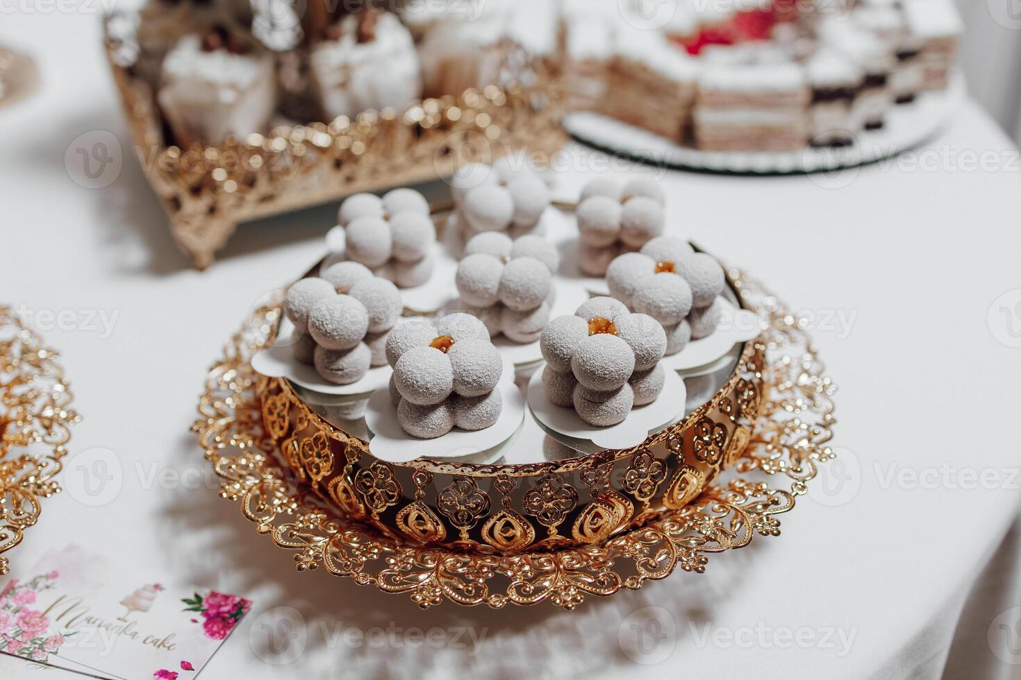 A tray of pastries with a floral design sits on a table. The pastries are small and round, and they are arranged in a way that makes them look like flowers. The tray is made of gold photo
