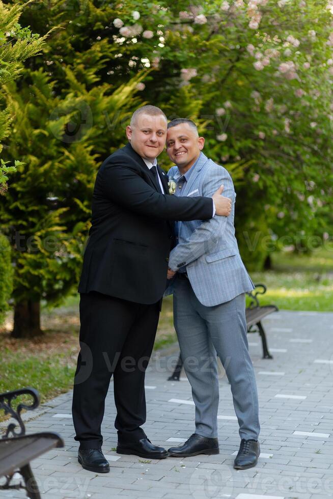 A man and a woman are posing for a picture in a park. The man is wearing a suit and tie, while the woman is wearing a dress. Scene is happy and celebratory photo