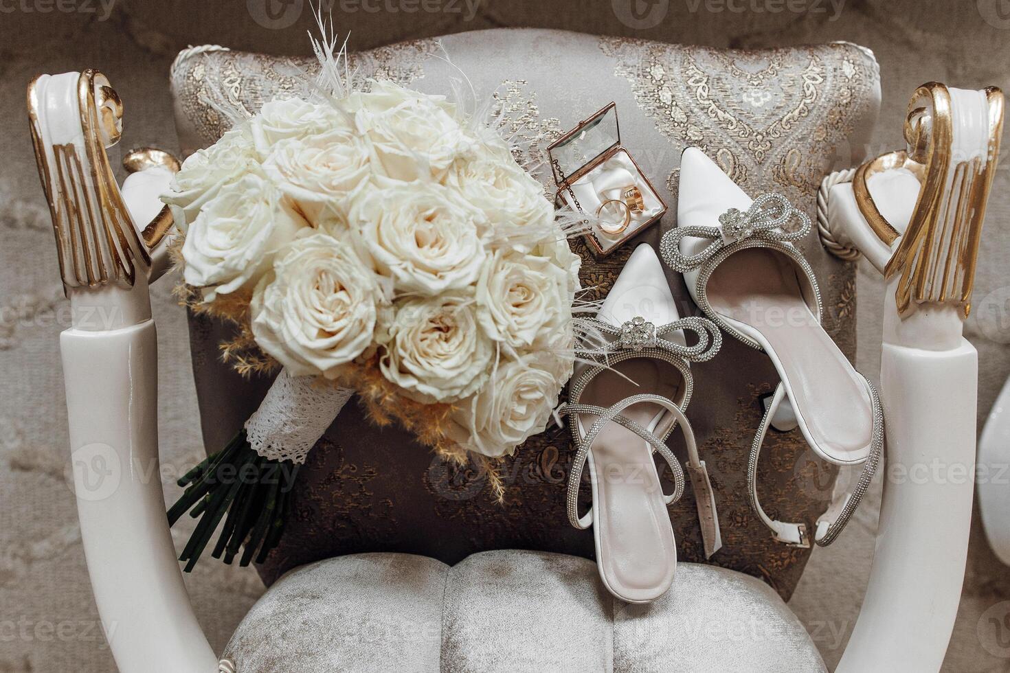 A white chair with a bouquet of white roses and a box of white shoes on it. The arrangement gives off a sense of elegance and sophistication photo