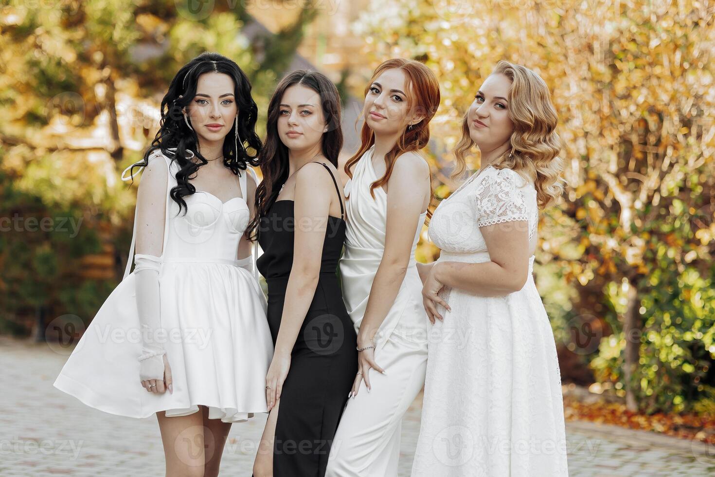 Four women in white and black dresses pose for a photo. Scene is elegant and sophisticated photo