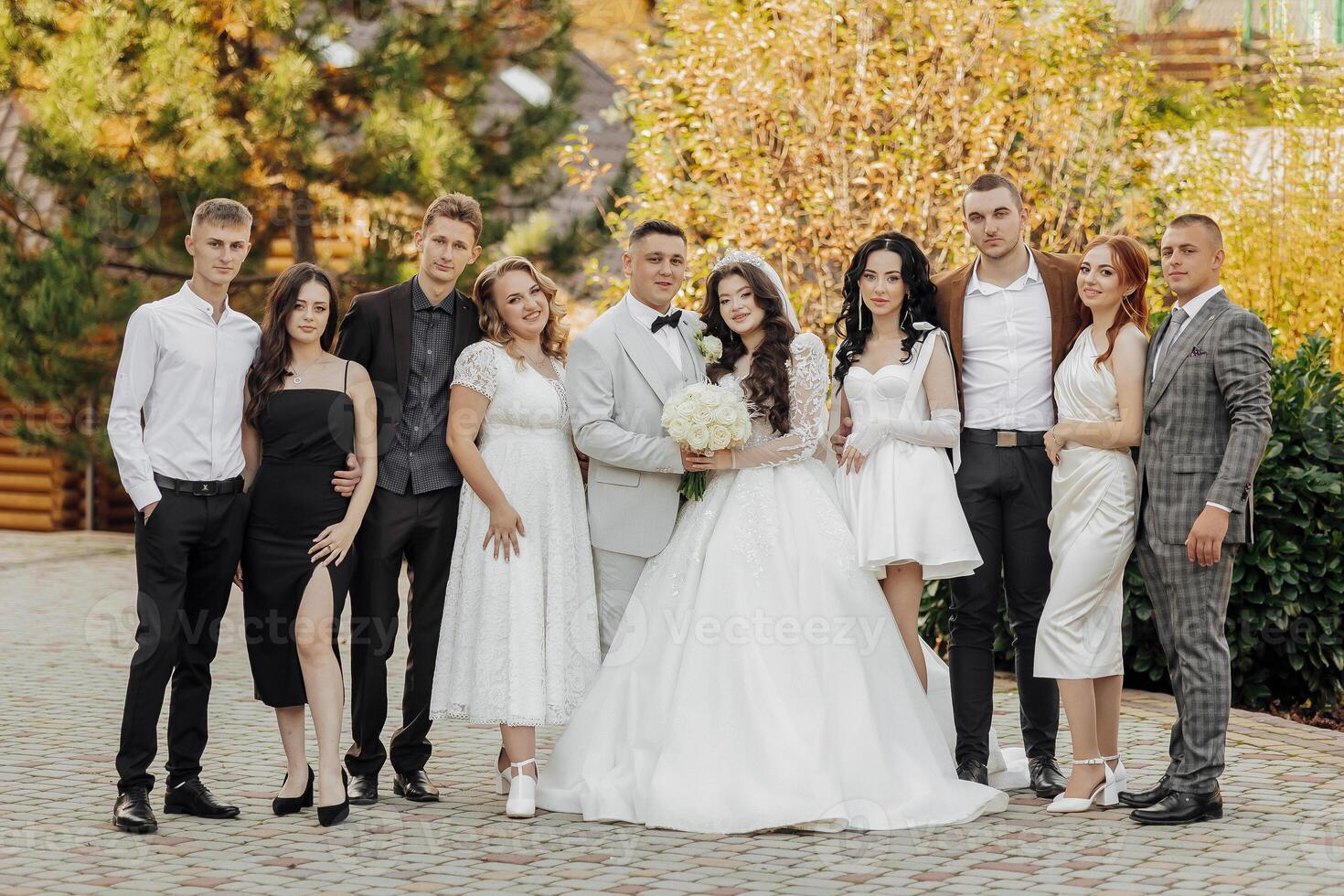 A group of people are posing for a picture, including a bride and groom photo