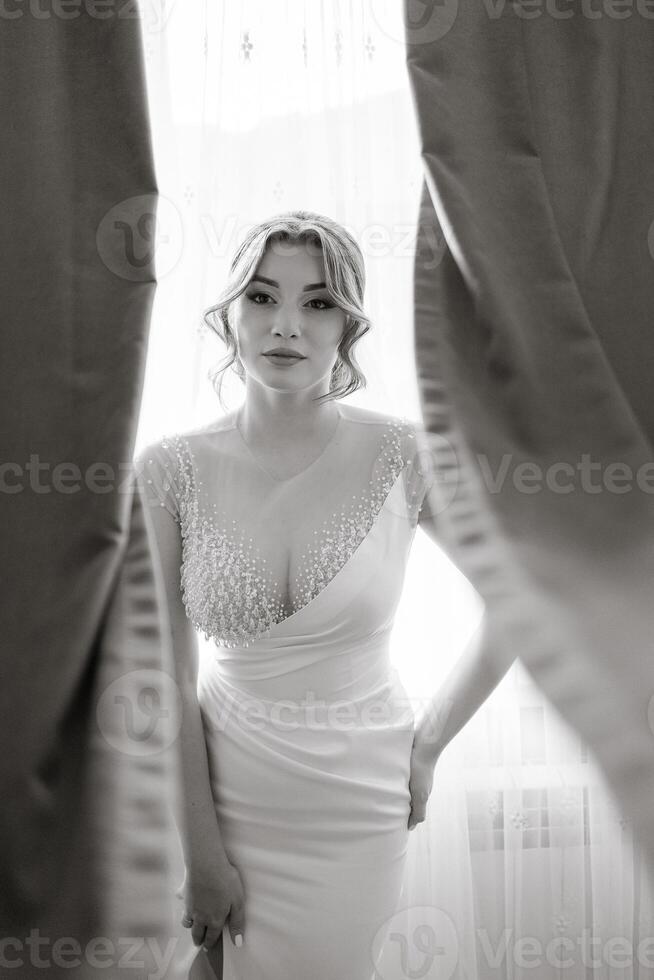 A woman in a white dress is standing in front of a curtain photo
