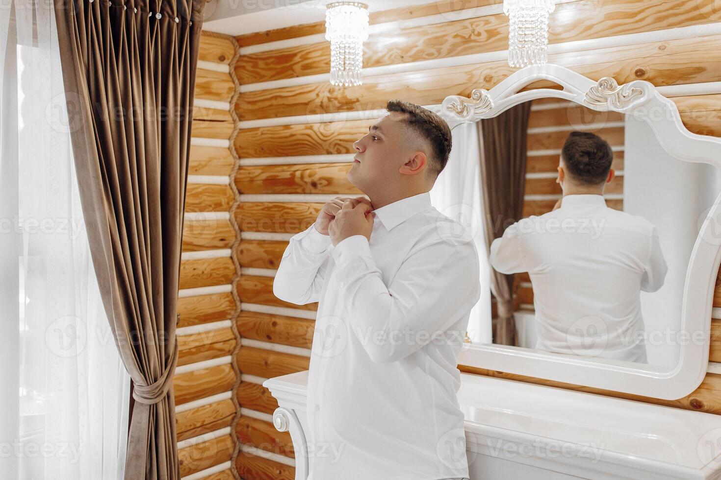 A man is getting ready for a wedding and is adjusting his tie photo