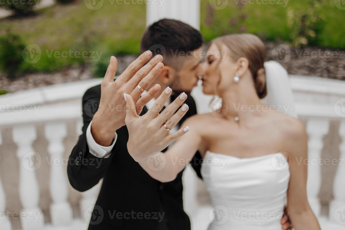 A bride and groom are kissing each other's hands, with the bride wearing a white dress. Concept of love and commitment, as the couple shares a tender moment together photo
