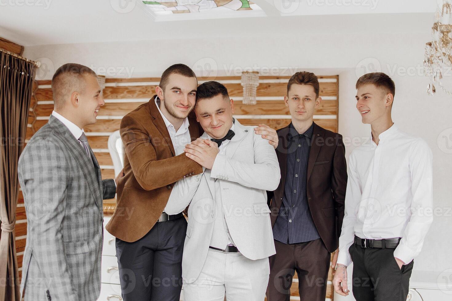 A group of men are hugging each other in a room. Scene is warm and friendly photo