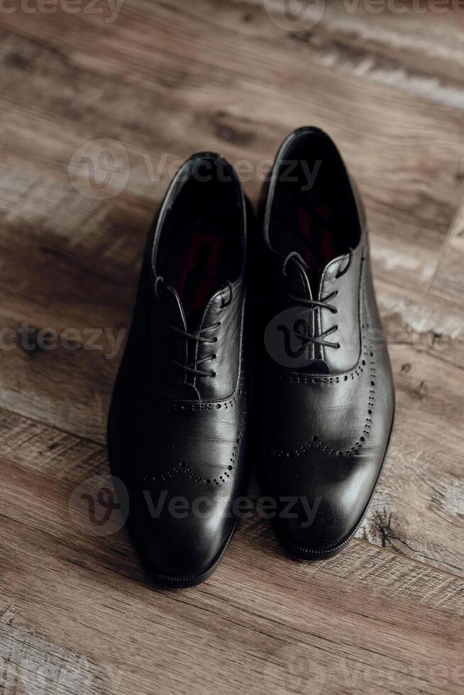 Two black dress shoes with red laces are standing on a wooden floor. The shoes are well-polished and appear to be made of leather. Concept of elegance and sophistication photo