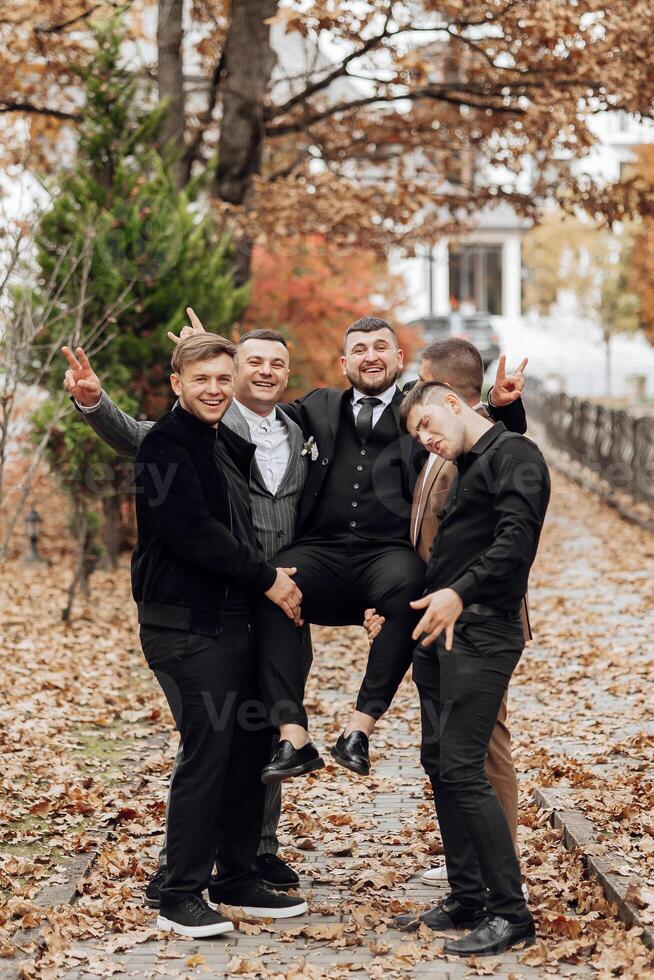 A group of men are posing for a picture, with one man holding another man up. Scene is lighthearted and fun, as the men are enjoying themselves and posing for the camera photo