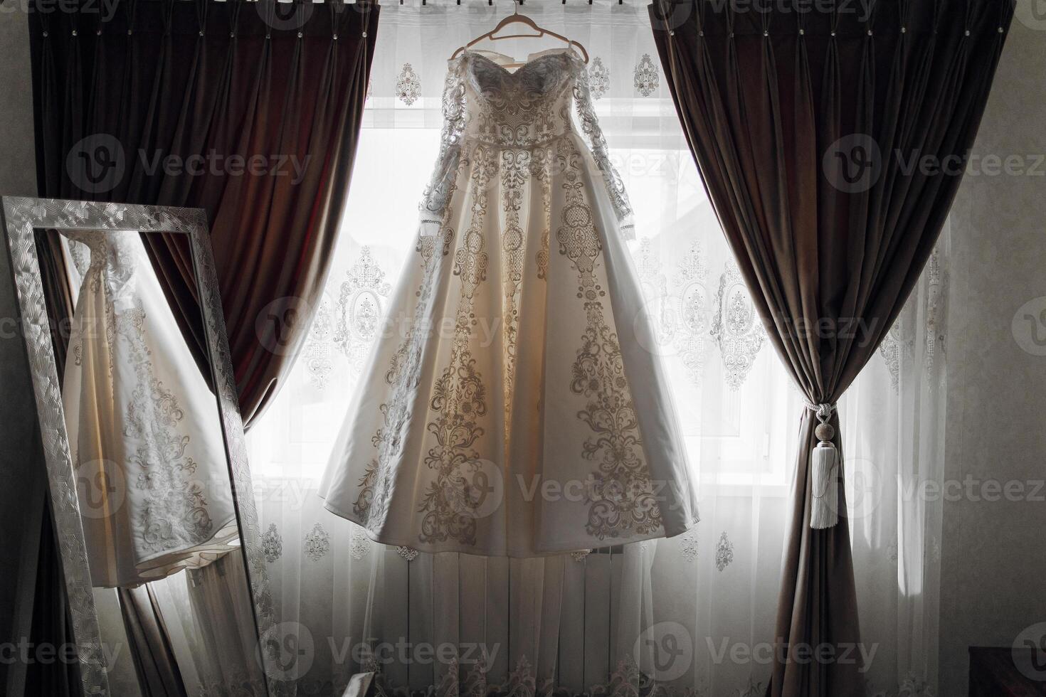 A white dress is hanging in front of a mirror photo