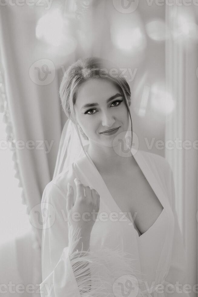 A woman is wearing a white robe and is smiling. She is posing for a picture. The photo is in black and white