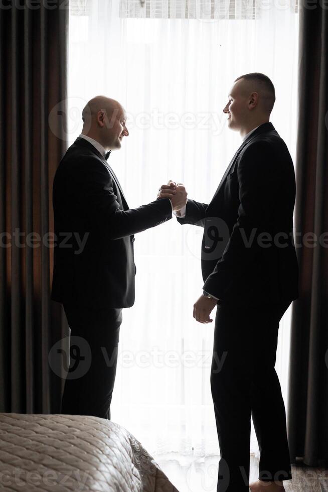 Two men shaking hands in a hotel room. Scene is professional and formal. The idea of the image is that of two men shaking hands, possibly in a business setting photo