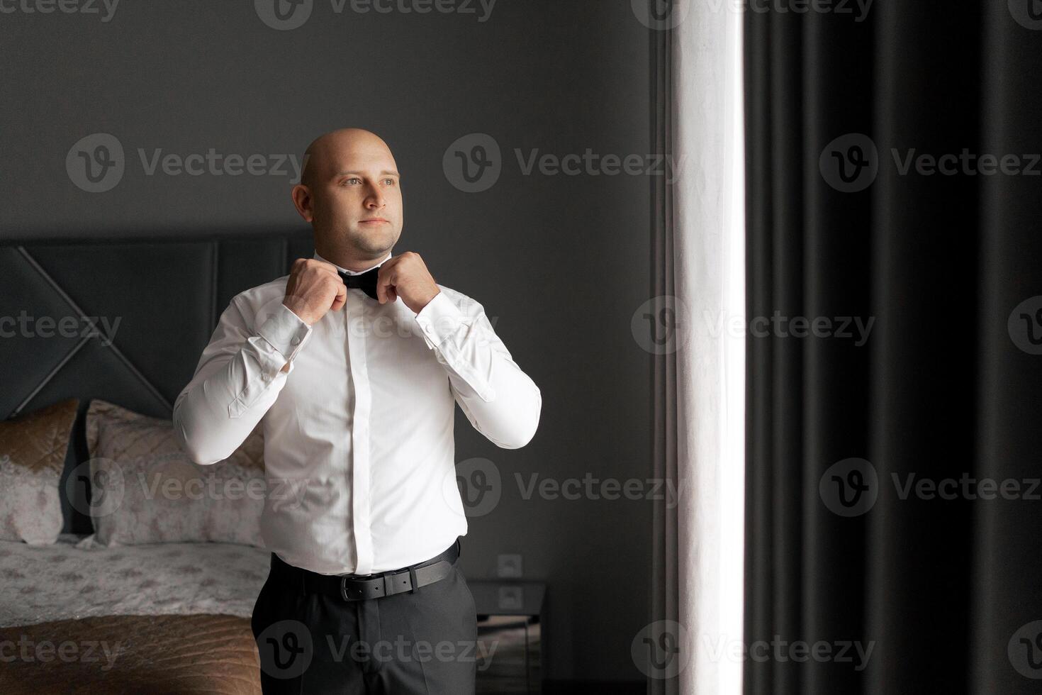 A man in a suit is getting ready to tie his bow tie. Concept of formality and preparation for a special occasion photo