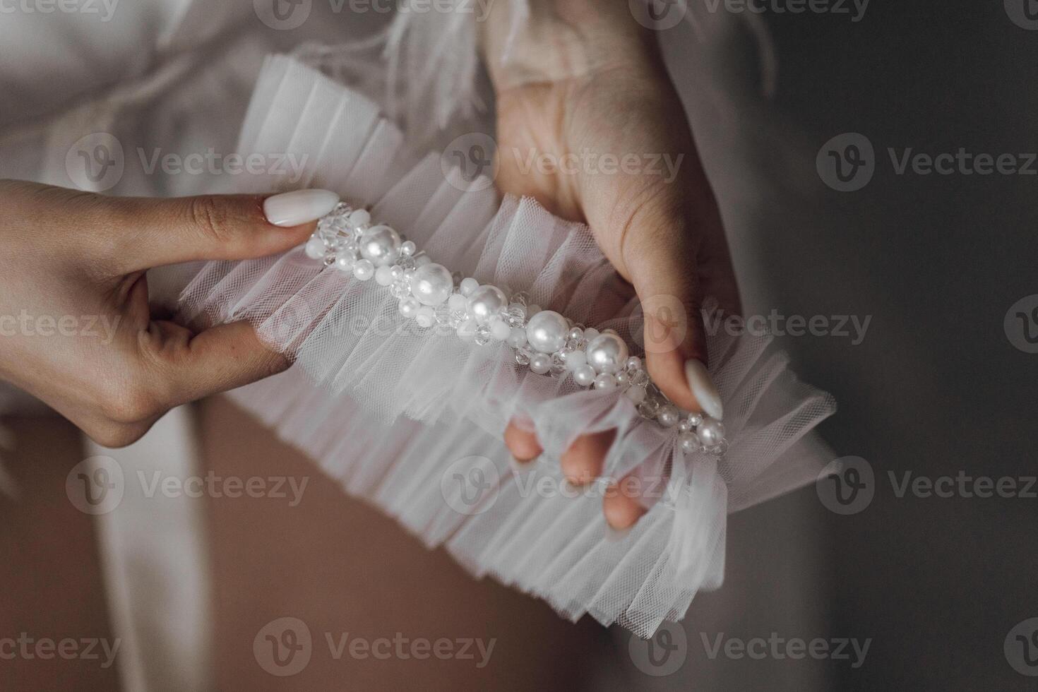 A woman is holding a white lace train with pearls on it photo