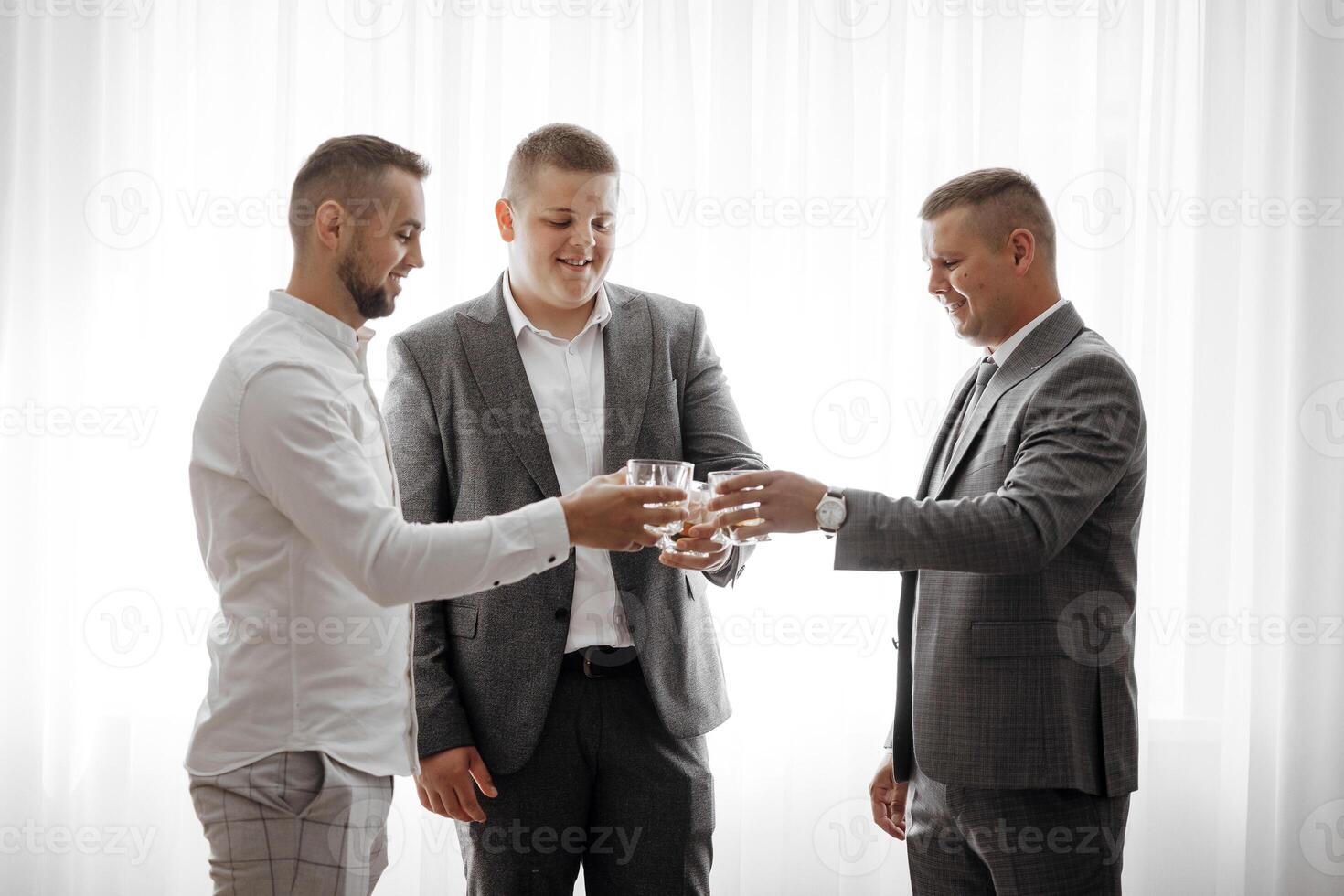 Three men in suits are toasting each other with glasses of wine. Scene is celebratory and friendly photo