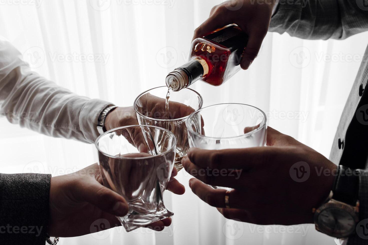 Three people are holding glasses and pouring liquor into them photo