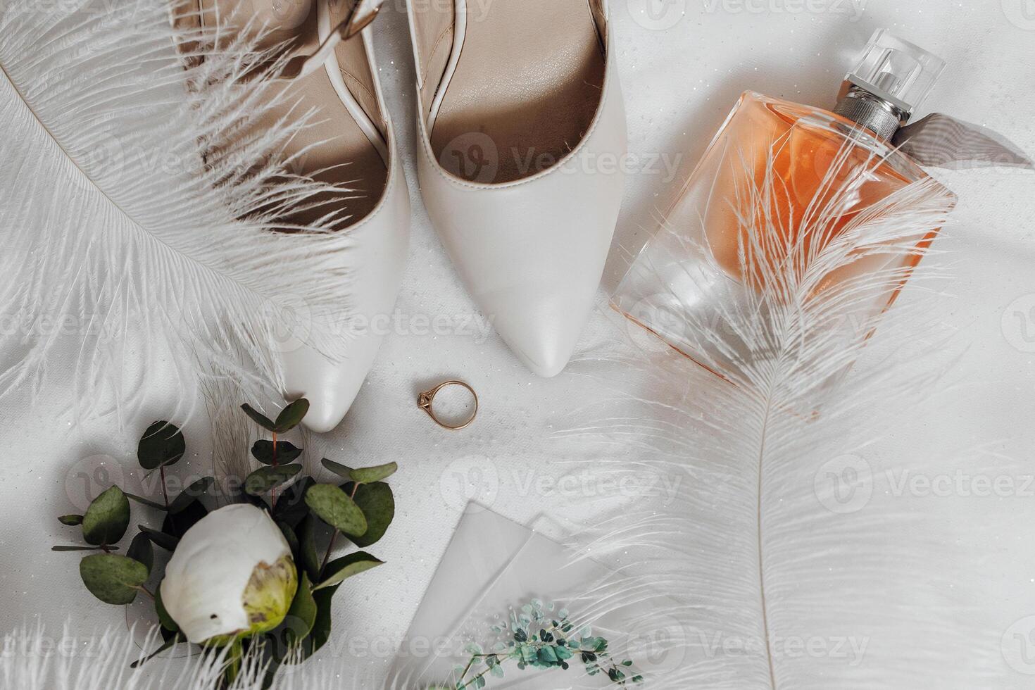 A pair of white shoes and a bottle of perfume are on a white surface photo