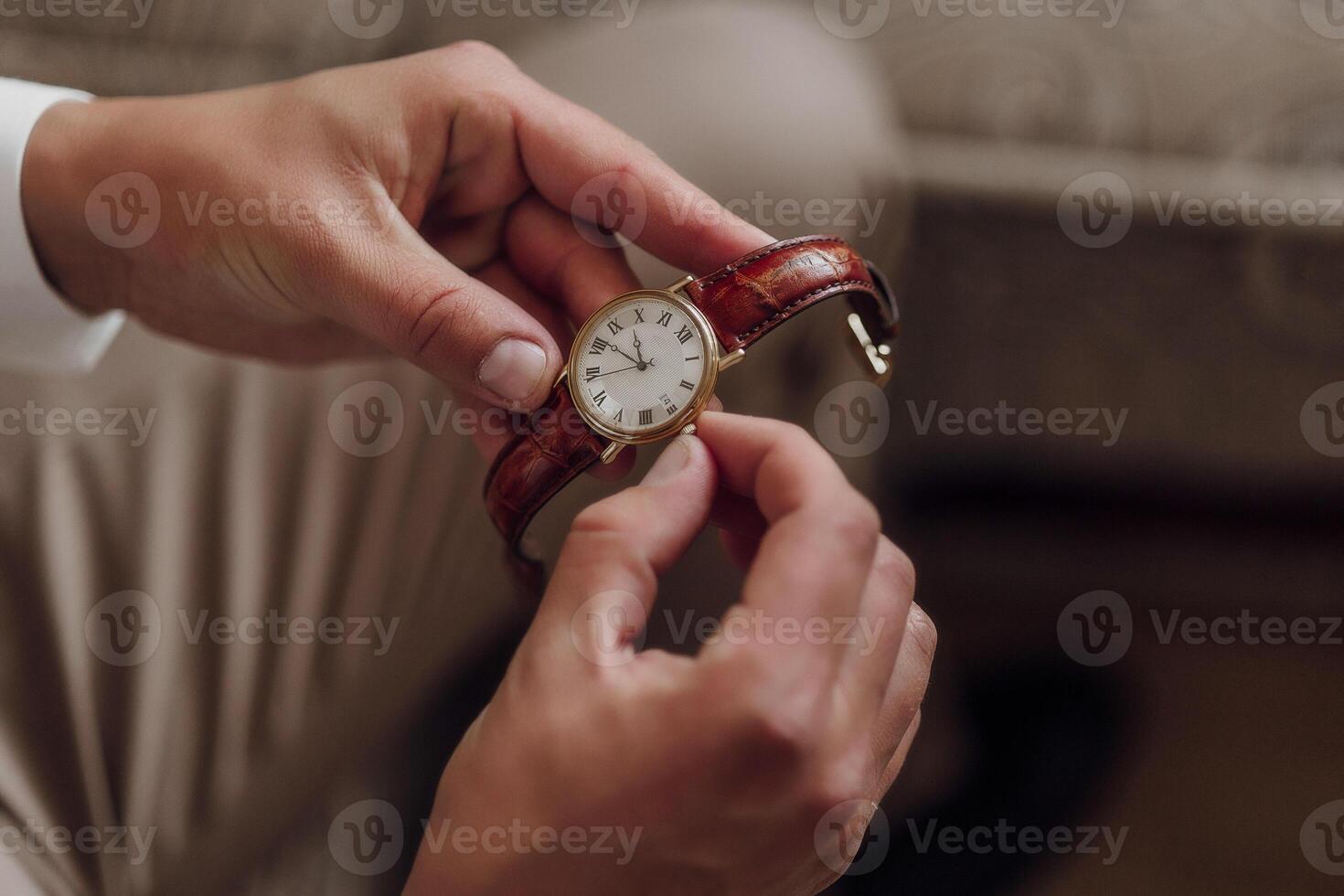 A person is holding a watch with a brown band photo